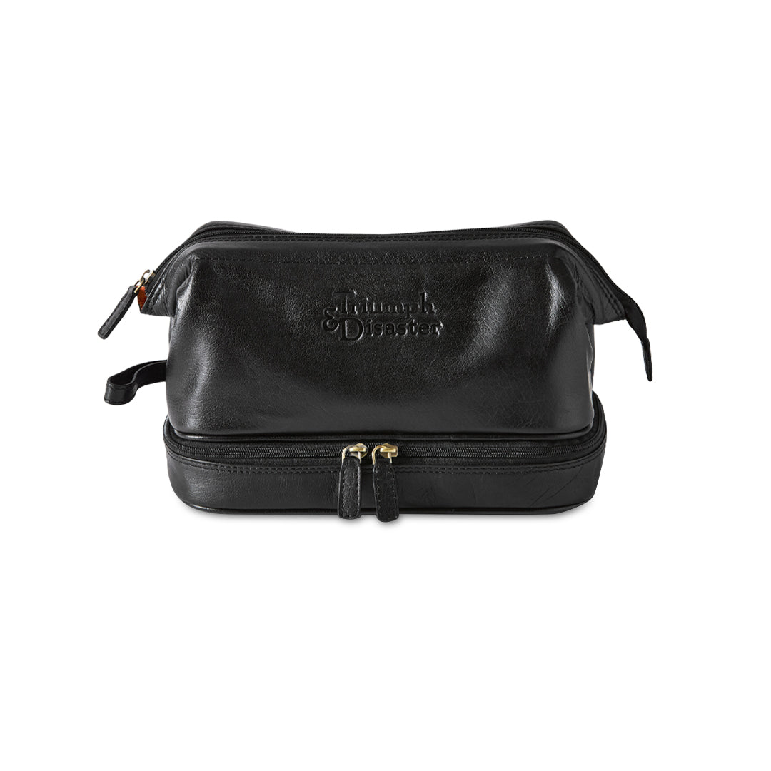 Black leather toiletry bag with gold zipper on a white background